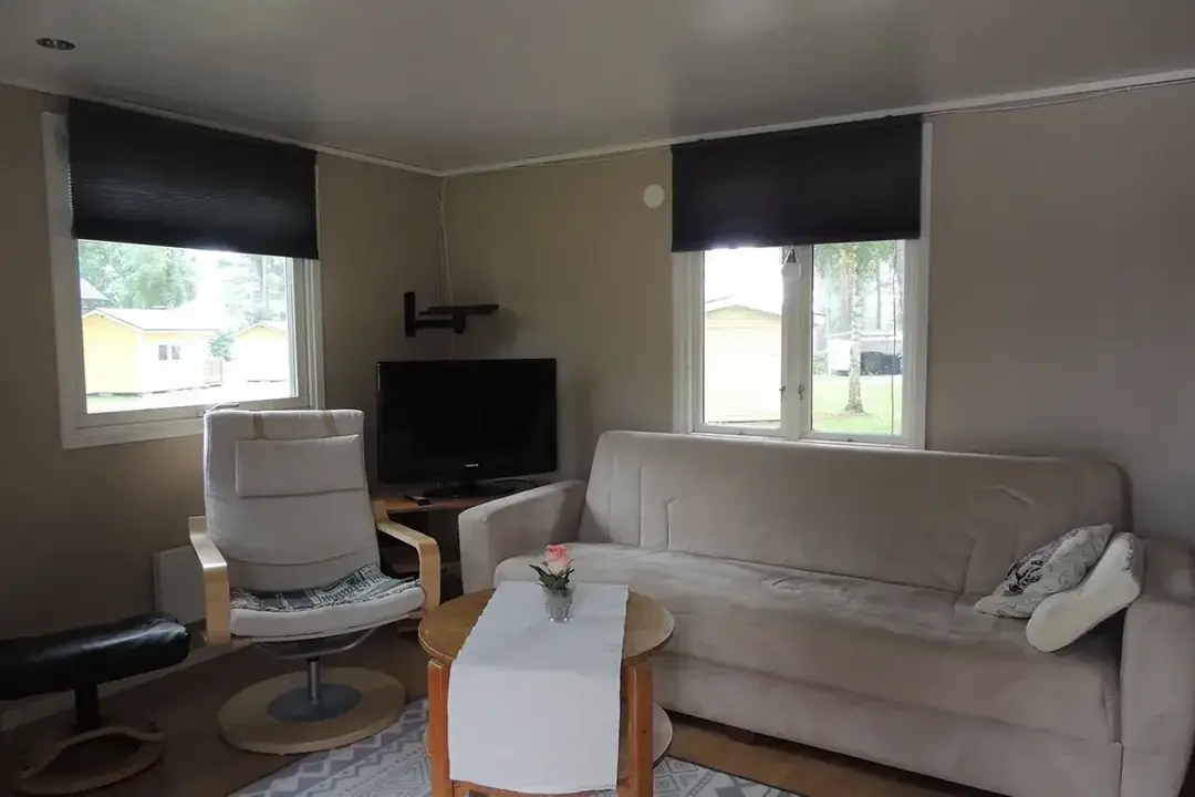 Ljust vardagsrum i stuga med soffa, fåtölj och tv
