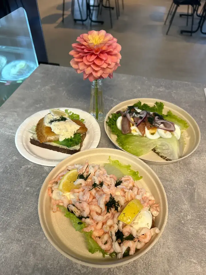 Räkmacka och fiskrätter på tallrikar med dahlia i vas på bordet