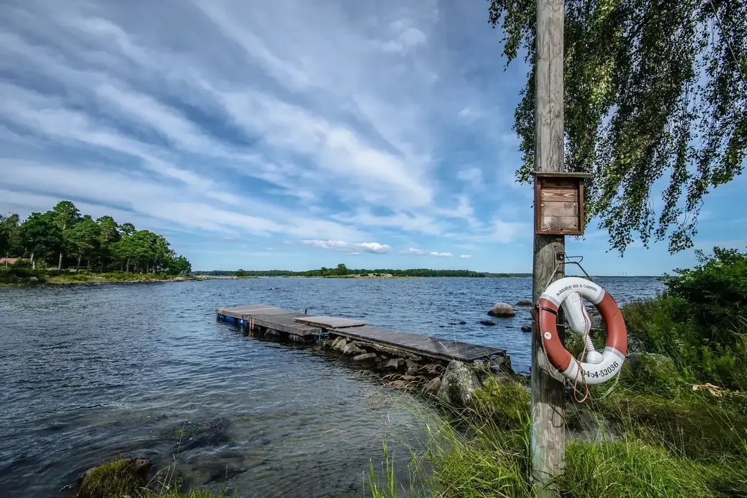 Träbrygga vid havet med livboj på stolpe i förgrunden